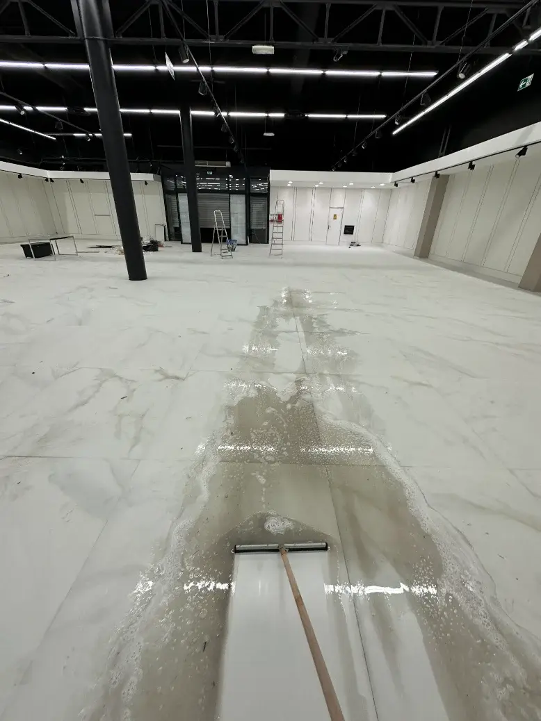 Raclage de l’eau de lavage sur un grand sol carrelé lors d’une remise en état