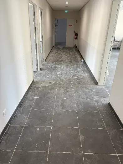 Avant : couloir au carrelage gris couvert de poussière de chantier